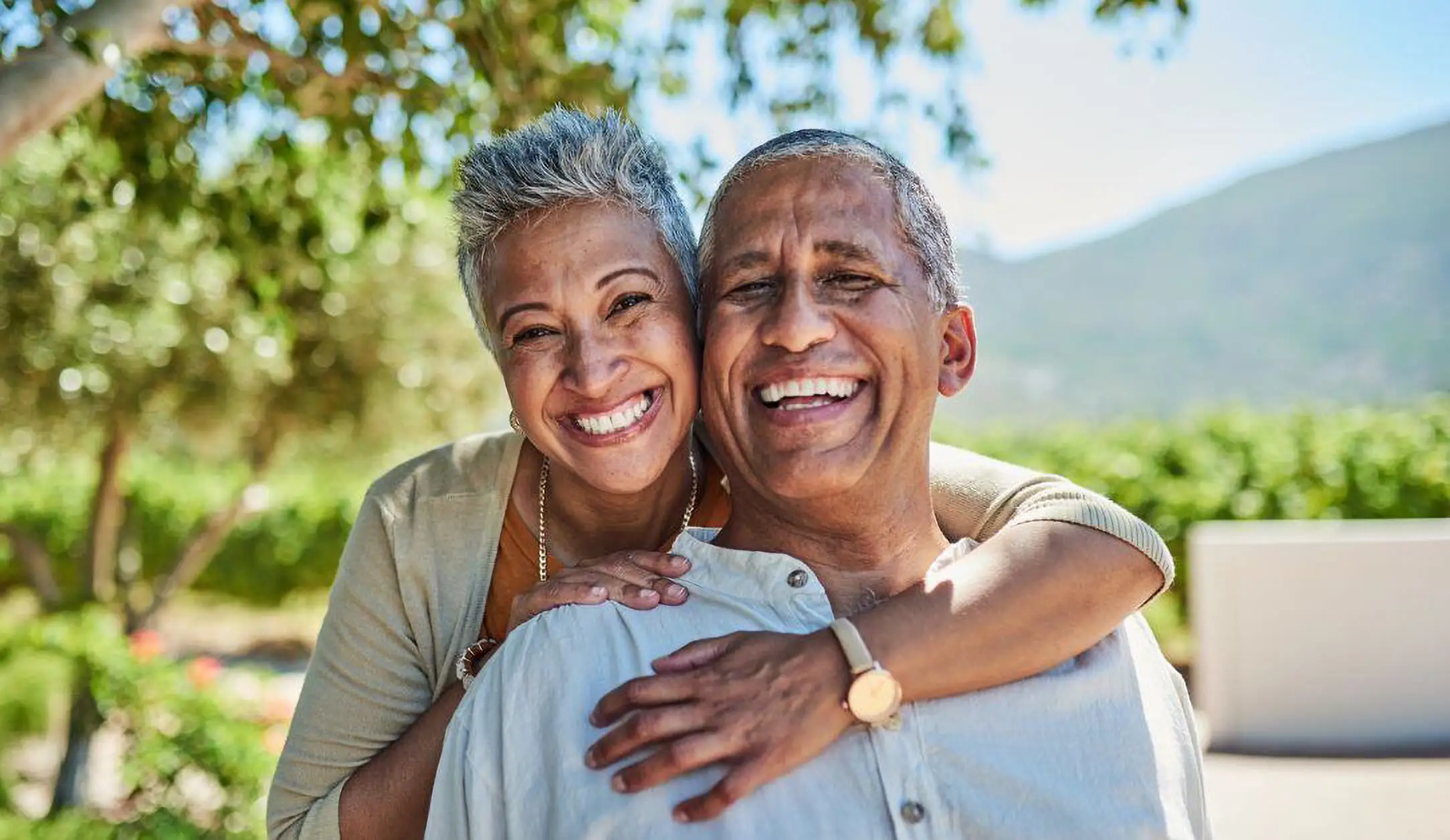 A senior couple smiling and hugging outside of Country Crest Senior Living, a 55+ community in Oroville, CA.